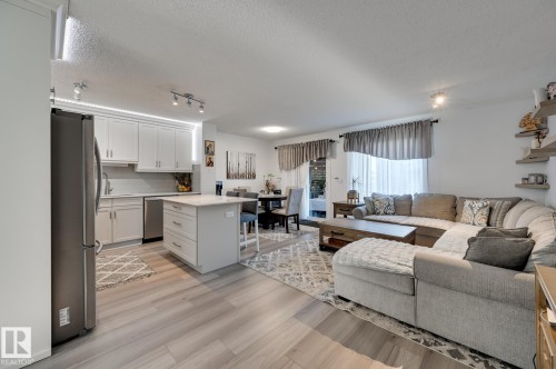 Living room featuring a textured ceiling and light wood-style floors - 59 14803 Miller Boulevard, Edmonton, AB - Indoor