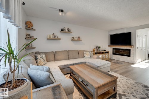 Living room with light wood finished floors, a glass covered fireplace, and a textured ceiling - 59 14803 Miller Boulevard, Edmonton, AB - Indoor Photo Showing Living Room