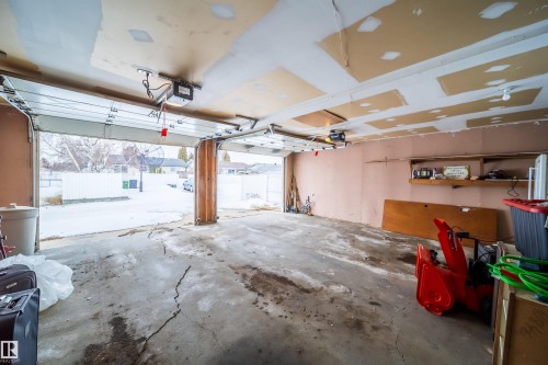 The property features a two-car garage with overhead doors and an exposed ceiling - 7911 145 Avenue Nw, Edmonton, AB - Indoor Photo Showing Garage