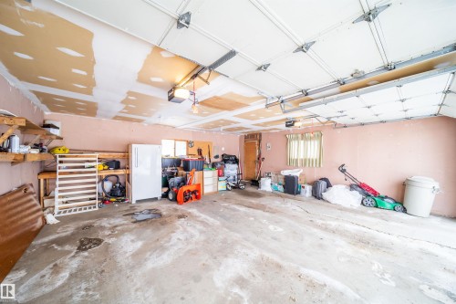 The property features an attached garage with a concrete floor, built-in shelving, and a garage door opener - 7911 145 Avenue Nw, Edmonton, AB - Indoor Photo Showing Garage