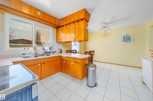 The kitchen features wood cabinetry, a double basin sink, and tile flooring - 7911 145 Avenue Nw, Edmonton, AB - Indoor Photo Showing Kitchen With Double Sink