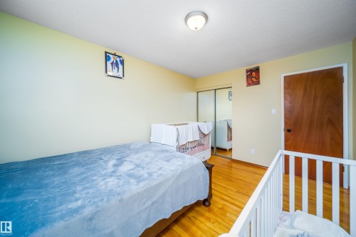This room features light-colored walls and polished hardwood flooring, complemented by a ceiling-mounted light fixture - 7911 145 Avenue Nw, Edmonton, AB - Indoor Photo Showing Bedroom