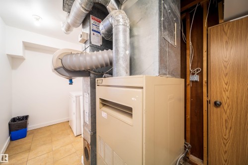 Utility area featuring a furnace, exposed ductwork, and tile flooring - 7911 145 Avenue Nw, Edmonton, AB - Indoor