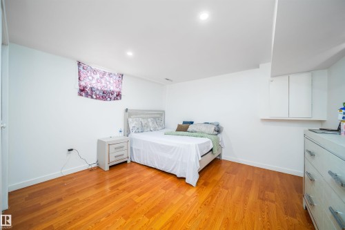 This room features polished hardwood flooring and white walls, creating a bright and inviting atmosphere - 7911 145 Avenue Nw, Edmonton, AB - Indoor Photo Showing Bedroom