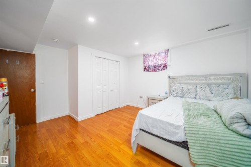 This room features hardwood floors, a white door with two white bi-fold closet doors, and white walls - 7911 145 Avenue Nw, Edmonton, AB - Indoor Photo Showing Bedroom