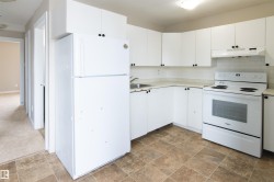 Kitchen with white appliances, white cabinets, and tasteful backsplash - 