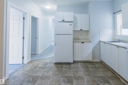Kitchen with white cabinets, freestanding refrigerator, backsplash, and stone finish floors - 