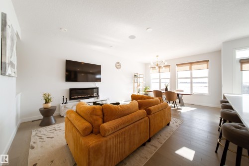Living area with a chandelier, wood finished floors, and a textured ceiling - 19 Sturtz Place, Leduc, AB - Indoor Photo Showing Living Room With Fireplace