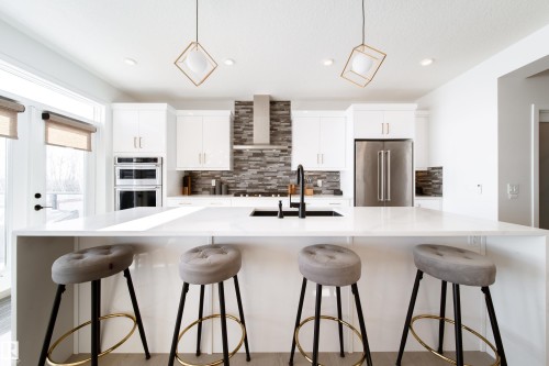 Kitchen featuring white cabinetry, a breakfast bar, a spacious island, and hanging light fixtures - 19 Sturtz Place, Leduc, AB - Indoor Photo Showing Kitchen With Upgraded Kitchen