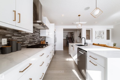 Kitchen featuring white cabinetry, light stone counters, stainless steel appliances, and tasteful backsplash - 19 Sturtz Place, Leduc, AB - Indoor Photo Showing Kitchen With Upgraded Kitchen