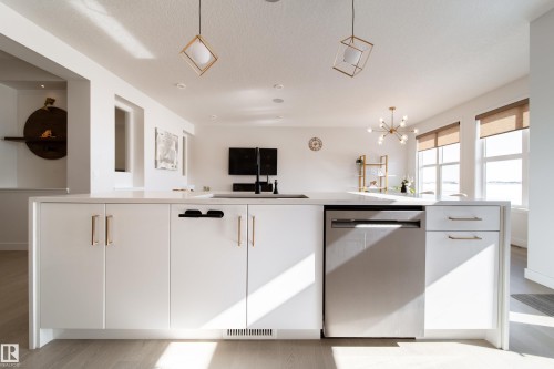 Kitchen with stainless steel dishwasher, an island with sink, modern cabinets, light wood-style floors, and white cabinetry - 19 Sturtz Place, Leduc, AB - Indoor Photo Showing Kitchen