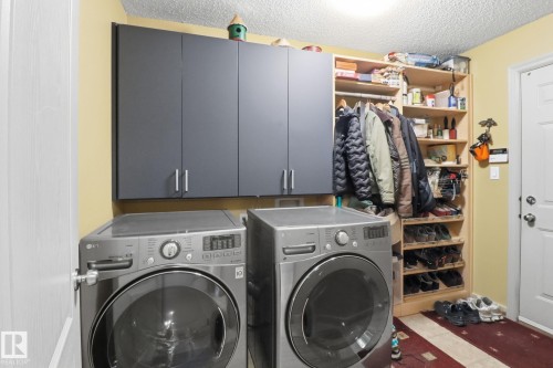 Laundry room with a textured ceiling, cabinet space, and washing machine and dryer - 8311 11 Avenue, Edmonton, AB - Indoor Photo Showing Laundry Room