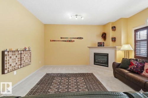 Living room featuring light carpet and a fireplace - 8311 11 Avenue, Edmonton, AB - Indoor With Fireplace