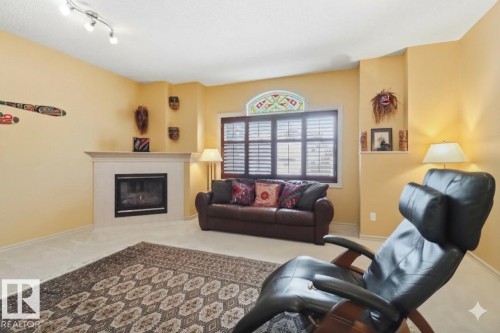 Carpeted living area with a glass covered fireplace and baseboards - 8311 11 Avenue, Edmonton, AB - Indoor Photo Showing Living Room With Fireplace