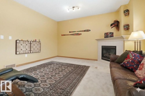Living room featuring light carpet and a tiled fireplace - 8311 11 Avenue, Edmonton, AB - Indoor With Fireplace