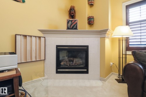 Detailed view of a tiled fireplace and carpet - 8311 11 Avenue, Edmonton, AB - Indoor Photo Showing Living Room With Fireplace
