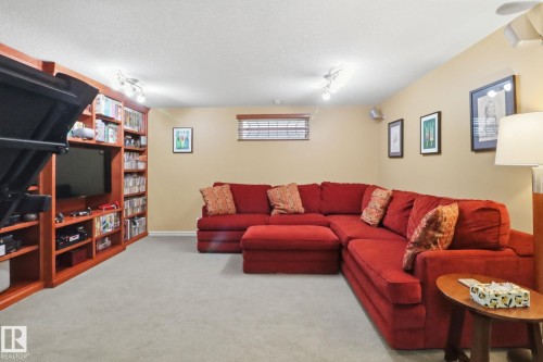 Living room featuring light carpet, track lighting, and a textured ceiling - 8311 11 Avenue, Edmonton, AB - Indoor