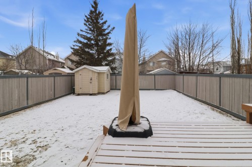 Snowy yard featuring a wooden deck, a shed, a fenced backyard, and a residential view - 8311 11 Avenue, Edmonton, AB - Outdoor