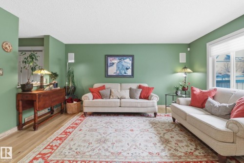 Living area featuring wood finished floors, a textured ceiling, and baseboard heating - 8311 11 Avenue, Edmonton, AB - Indoor Photo Showing Living Room