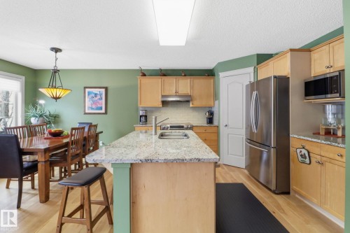 Kitchen with stainless steel appliances, light wood finish cabinets, light stone counters, light wood-style flooring, and a textured ceiling - 8311 11 Avenue, Edmonton, AB - Indoor Photo Showing Kitchen With Stainless Steel Kitchen With Double Sink