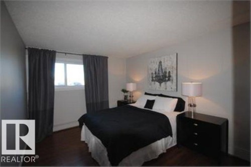 This room features dark hardwood flooring, light grey walls, and a window with dark grey curtains - 12 11265 31 Avenue, Edmonton, AB - Indoor Photo Showing Bedroom