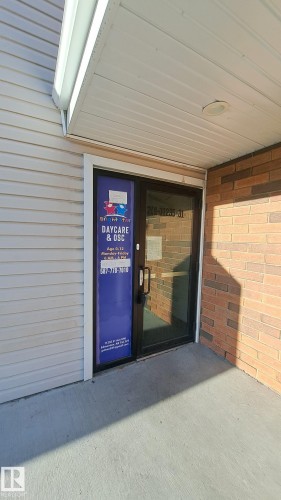 The property features a concrete entryway with a glass door, light-colored siding, and brick accents - 12 11265 31 Avenue, Edmonton, AB -  With Exterior