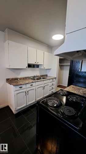 The kitchen features white cabinetry, a double basin sink, and an electric range with an overhead exhaust fan - 12 11265 31 Avenue, Edmonton, AB - Indoor Photo Showing Kitchen With Double Sink