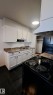 The kitchen features white cabinetry, a double basin sink, and an electric range with an overhead exhaust fan - 12 11265 31 Avenue, Edmonton, AB  - Indoor Photo Showing Kitchen With Double Sink 