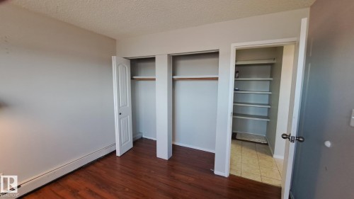 This room features rich hardwood flooring, a fresh coat of light-colored paint on the walls, and a textured ceiling - 12 11265 31 Avenue, Edmonton, AB - Indoor Photo Showing Other Room