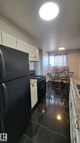 Well-appointed kitchen featuring black appliances, granite-style countertops, and white cabinetry - 12 11265 31 Avenue, Edmonton, AB - Indoor Photo Showing Kitchen