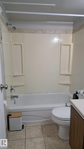 Bathroom featuring a bathtub with an integrated shower, tiled flooring, and a toilet - 12 11265 31 Avenue, Edmonton, AB - Indoor Photo Showing Bathroom