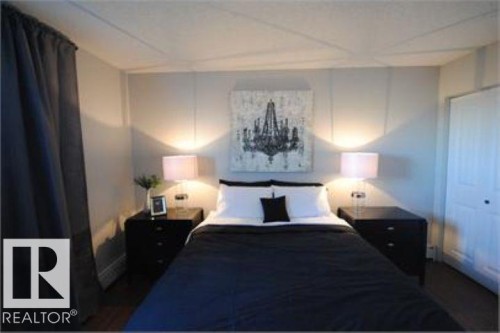 The bedroom features a light grey wall with vertical paneling, dark flooring, and a white closet door - 12 11265 31 Avenue, Edmonton, AB - Indoor Photo Showing Bedroom