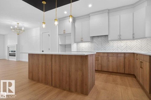 Kitchen featuring light wood-style floors, decorative backsplash, a center island, wood finish cabinetry, and suspended lighting - 45 Rosa Crescent, St. Albert, AB - Indoor Photo Showing Kitchen