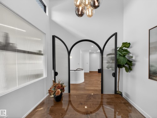 Corridor featuring suspended lighting, arched walkways, and dark wood-type flooring - 7104 54 Avenue, Beaumont, AB - Indoor Photo Showing Other Room