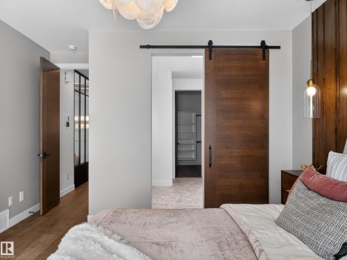 Bedroom with a barn door and wood finished floors - 7104 54 Avenue, Beaumont, AB - Indoor Photo Showing Bedroom