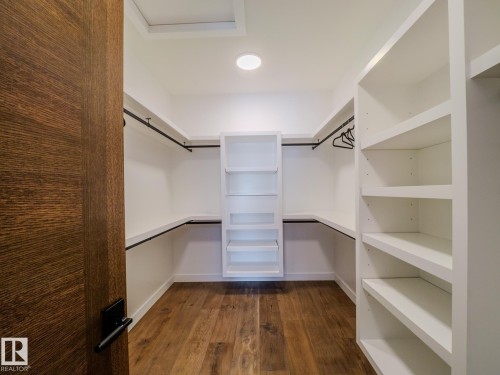 Walk in closet with dark wood-style flooring and attic access - 7104 54 Avenue, Beaumont, AB - Indoor With Storage