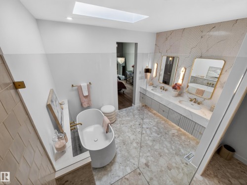 Bathroom featuring a freestanding tub, a skylight, double vanity, ensuite bathroom, and an accent wall - 7104 54 Avenue, Beaumont, AB - Indoor