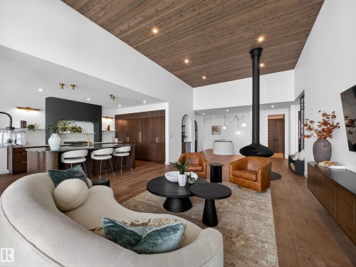 Living room featuring a high wooden ceiling, dark wood-style floors, recessed lighting, arched walkways, and a wood stove - 7104 54 Avenue, Beaumont, AB - Indoor Photo Showing Living Room