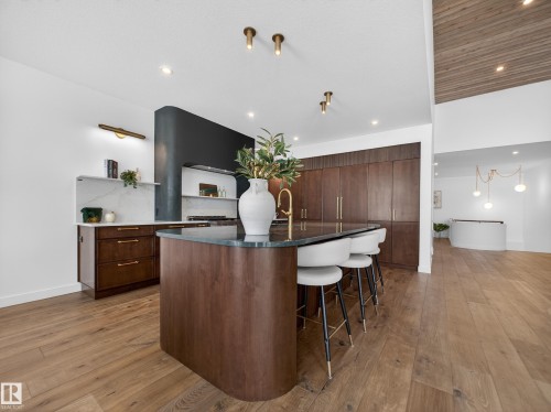 Kitchen featuring light wood-style floors, dark wood finish cabinetry, a kitchen breakfast bar, modern cabinets, and open shelves - 7104 54 Avenue, Beaumont, AB - Indoor