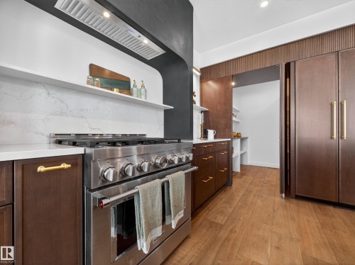 Kitchen with open shelves, high end stainless steel range oven, light wood-style flooring, dark wood finish cabinetry, and recessed lighting - 7104 54 Avenue, Beaumont, AB - Indoor Photo Showing Kitchen With Upgraded Kitchen