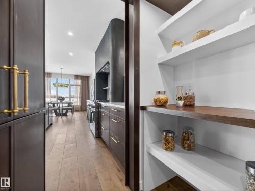 Kitchen featuring dark wood finish cabinetry, light wood-type flooring, recessed lighting, high end range, and light countertops - 7104 54 Avenue, Beaumont, AB - Indoor