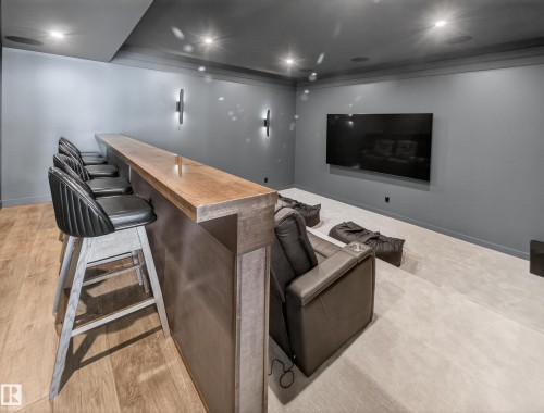 Home theater room with recessed lighting, light wood-style floors, ornamental molding, and bar - 7104 54 Avenue, Beaumont, AB - Indoor