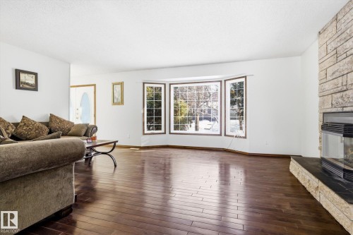 Living area with a stone fireplace, dark wood-style floors, and a textured ceiling - 83 Bellevue Crescent, St. Albert, AB - Indoor Photo Showing Living Room With Fireplace