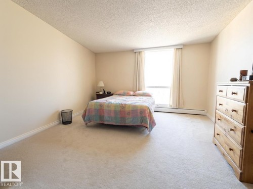Bedroom featuring light colored carpet, baseboard heating, and a textured ceiling - 1401 10883 Saskatchewan Drive, Edmonton, AB - Indoor Photo Showing Bedroom