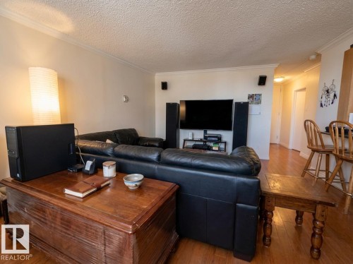 Living area featuring wood-type flooring, ornamental molding, and a textured ceiling - 1401 10883 Saskatchewan Drive, Edmonton, AB - Indoor Photo Showing Living Room