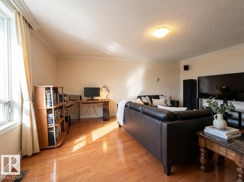 Living room featuring an office area, light wood finished floors, a textured ceiling, and crown molding - 1401 10883 Saskatchewan Drive, Edmonton, AB - Indoor