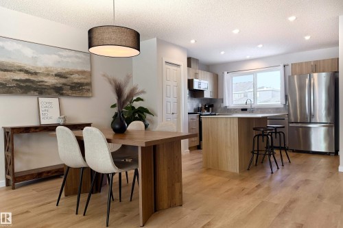 Kitchen with stainless steel appliances, a kitchen bar, pendant lighting, light wood-style flooring, and light countertops - 112 Stonehouse Way, Leduc, AB - Indoor
