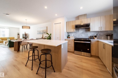 Kitchen with light wood finish cabinets, stainless steel appliances, a kitchen island, and modern cabinets - 112 Stonehouse Way, Leduc, AB - Indoor Photo Showing Kitchen