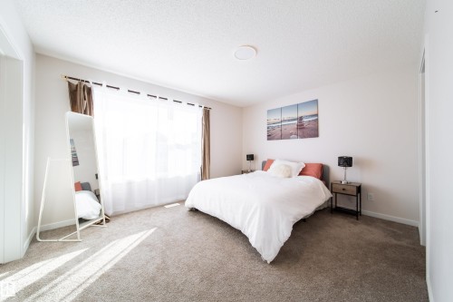 Carpeted bedroom featuring baseboards and a textured ceiling - 112 Stonehouse Way, Leduc, AB - Indoor Photo Showing Bedroom