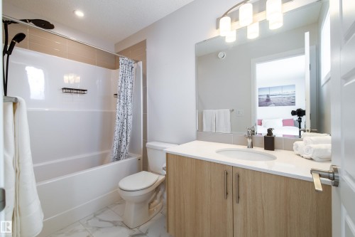 Ensuite bathroom with vanity, shower / tub combo with curtain, and light marble finish floors - 112 Stonehouse Way, Leduc, AB - Indoor Photo Showing Bathroom